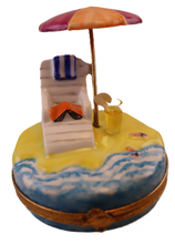 Lade das Bild in den Galerie-Viewer, A hand painted Limoges collectible box depicting a beach scene with a chair, umbrella, and drink.