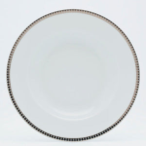 Round white plate with decorative rim on a light gray background